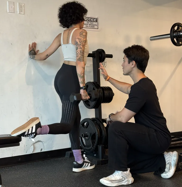 Client performing a Bulgarian split squat with a dumbbell, coached by Guilherme